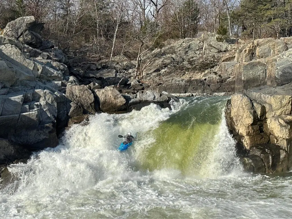 a kayaker kayaking through a rapid.
