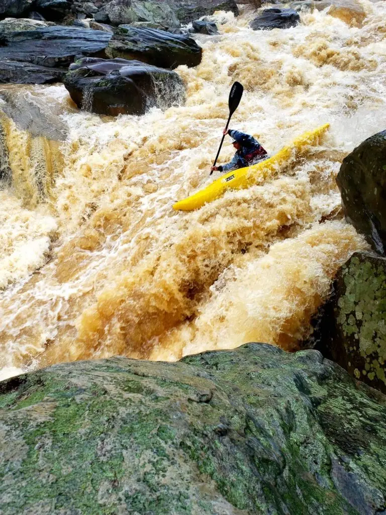 a kayaker kayaking through a rapid.