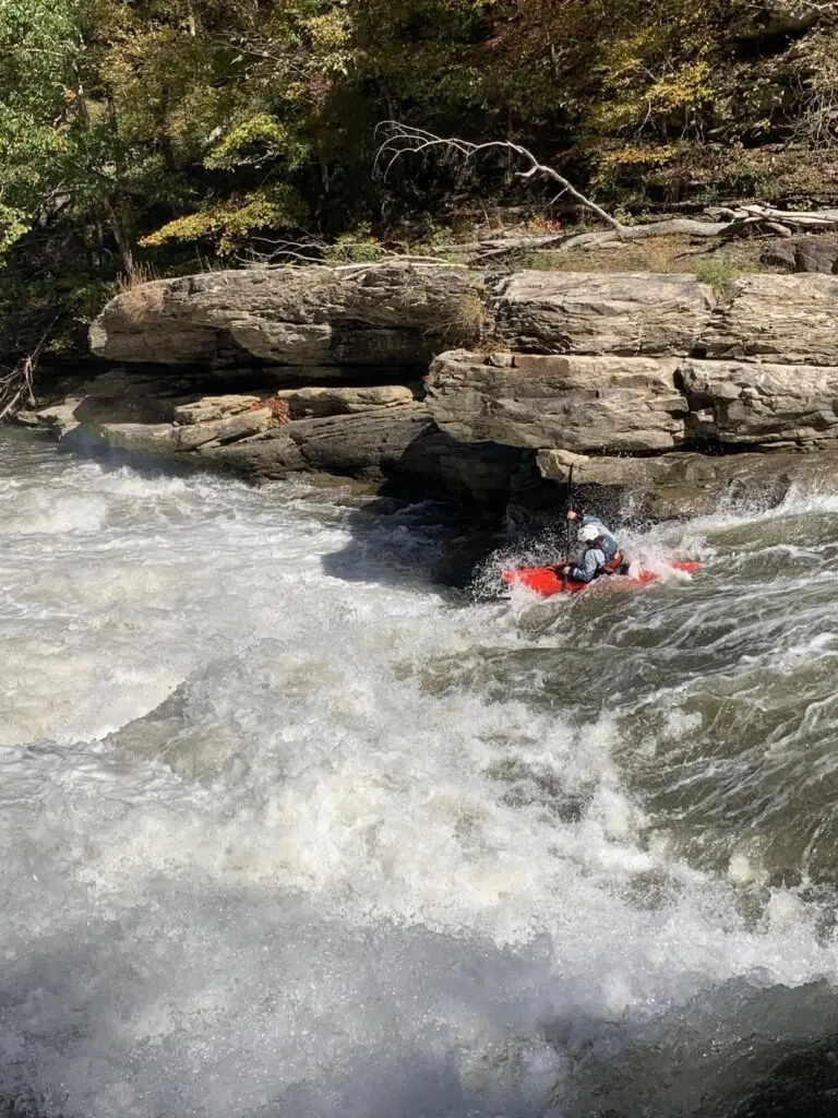 a kayaker kayaking through a rapid.